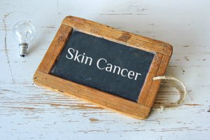 skin cancer on chalk board adjacent lightbulb